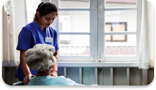 A nurse is offering support and comfort to an elderly patient seated in a wheelchair.