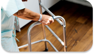 An elderly patient in a hospital, walking with the help of a walker.